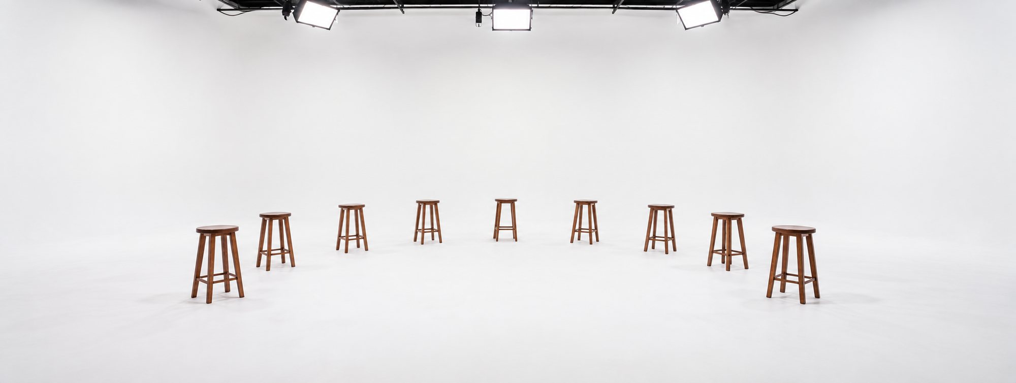 Nine wooden stools in a white studio, lit from a rig overhead. The set for Savvy Nigerian Originals.